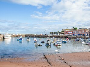 A harbor with various boats docked, a sandy beach, and buildings in the background.
