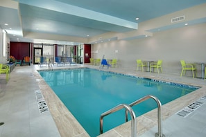 A swimming pool with a tiled deck, surrounded by bright yellow chairs and a few blue chairs. - Home2 Suites by Hilton Burleson (Burleson)