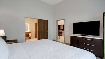 A hotel room with a large bed, a flat-screen TV, a wardrobe, and a bathroom visible through an open door.