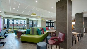 Ein moderner Loungebereich mit einem grünen Sofa, roten Sesseln und einem Holztisch.