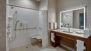 Een moderne badkamer met een douche, een wastafel met spiegel en een handdoekrek.