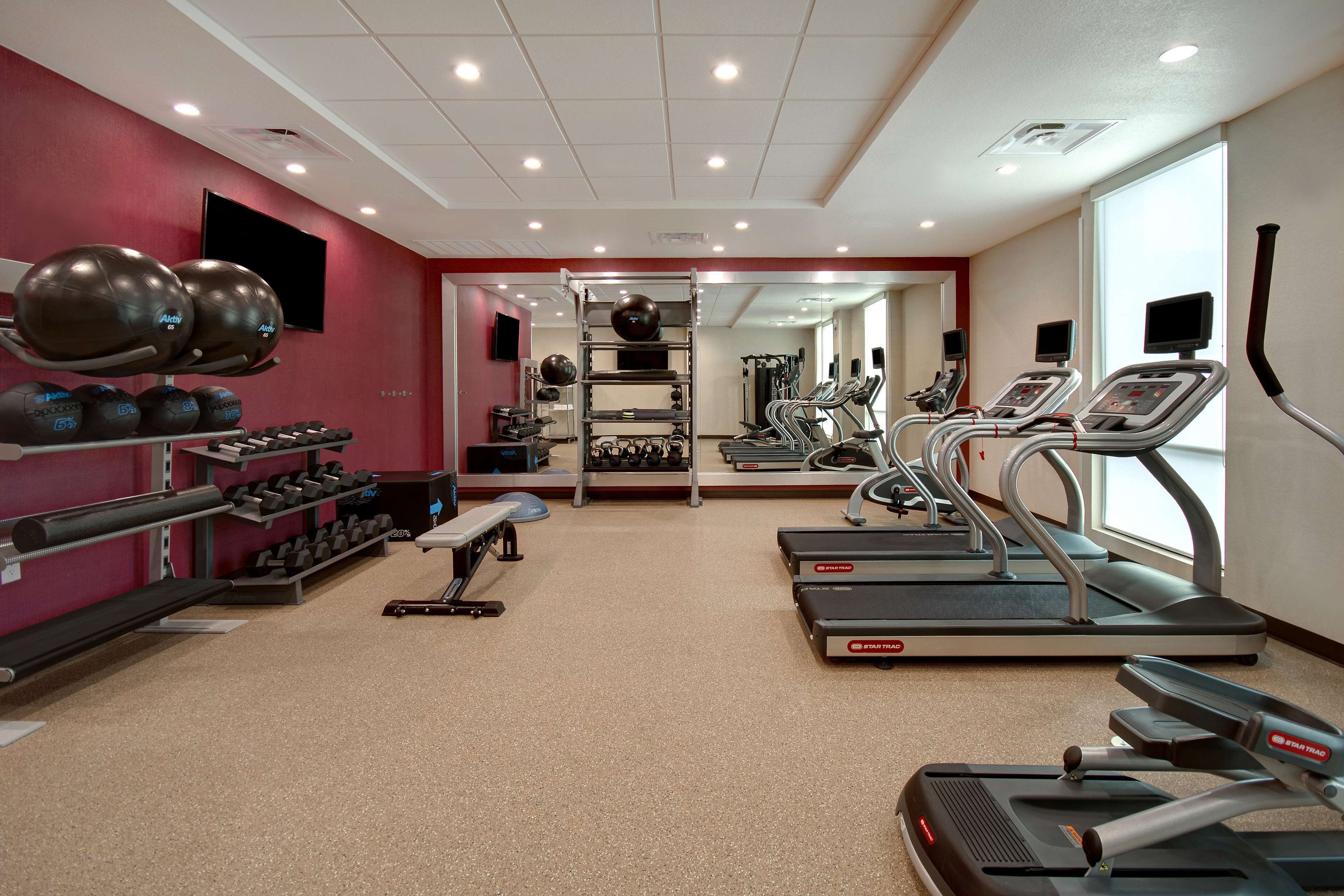 Une salle de sport équipée de tapis de course, d’haltères et de ballons d’exercice.