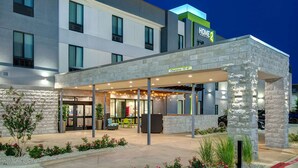 Ein Hotel Eingangsbereich mit überdachter Außenfläche, steinverkleideter Fassade und einem Schild, das eine Durchfahrtshöhe von 3,3 Metern für Barrierefreiheit anzeigt.