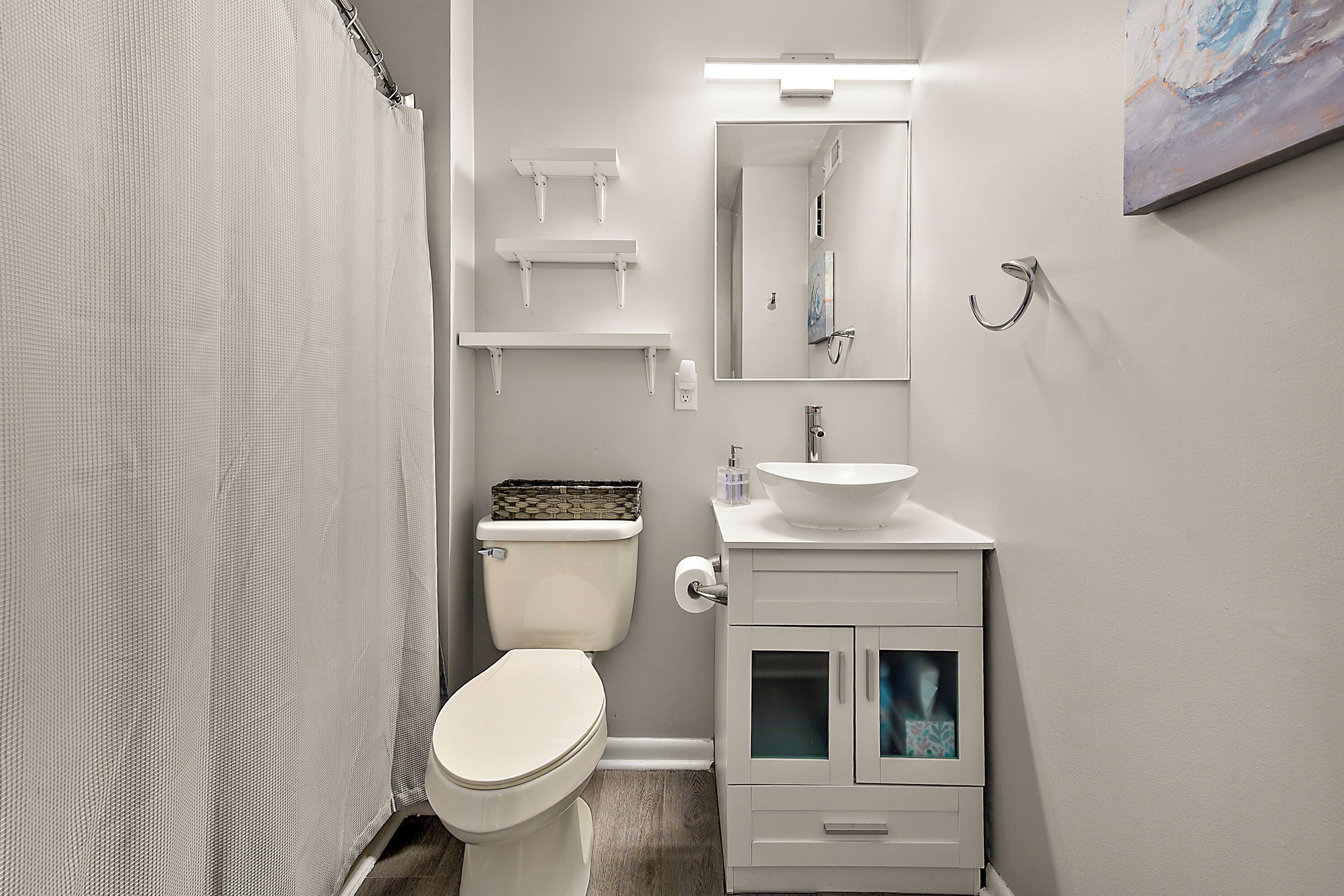 A bathroom with a toilet, a sink, a mirror, and a shower curtain.