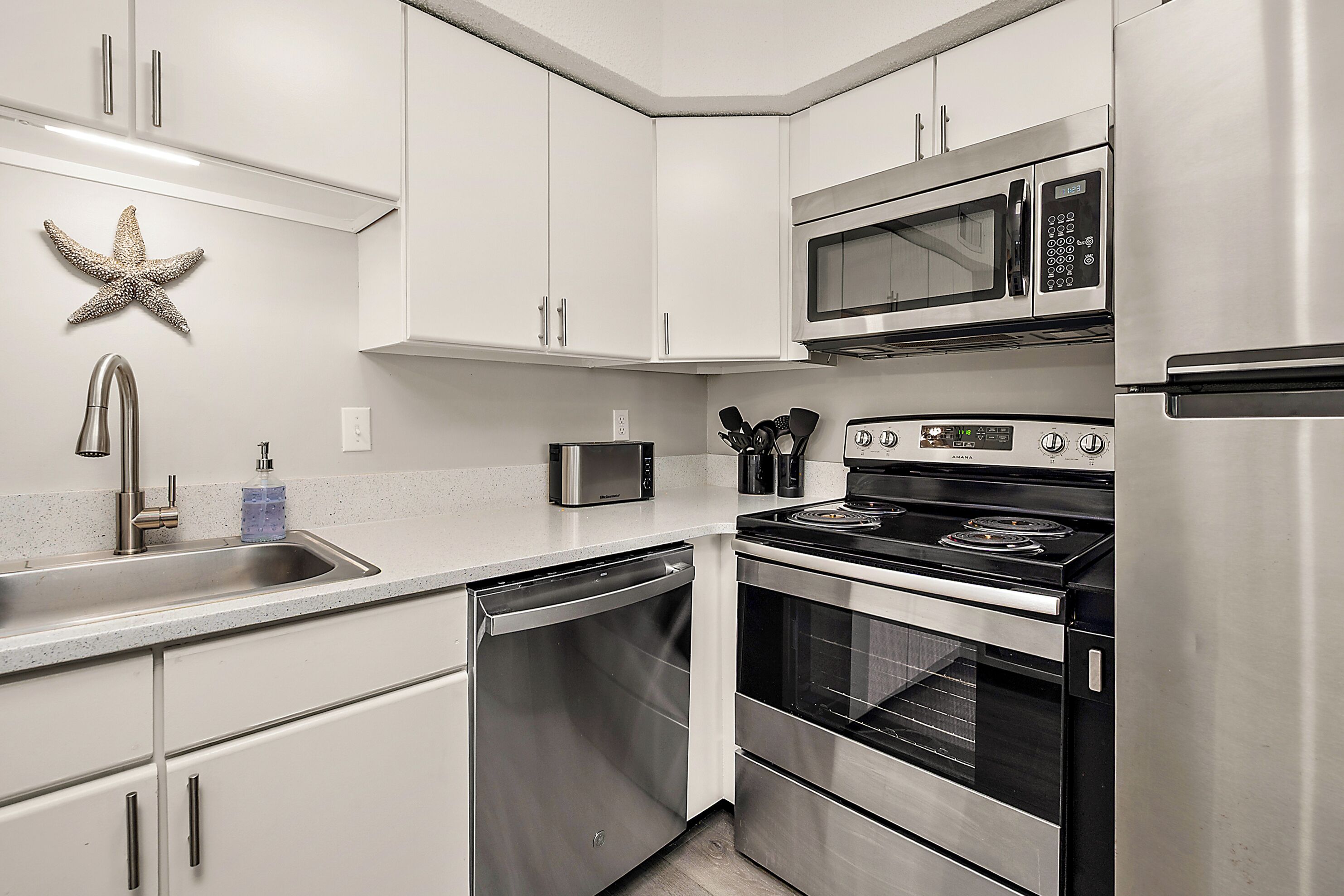 Una cocina moderna con electrodomésticos de acero inoxidable, muebles blancos y lavavajillas.