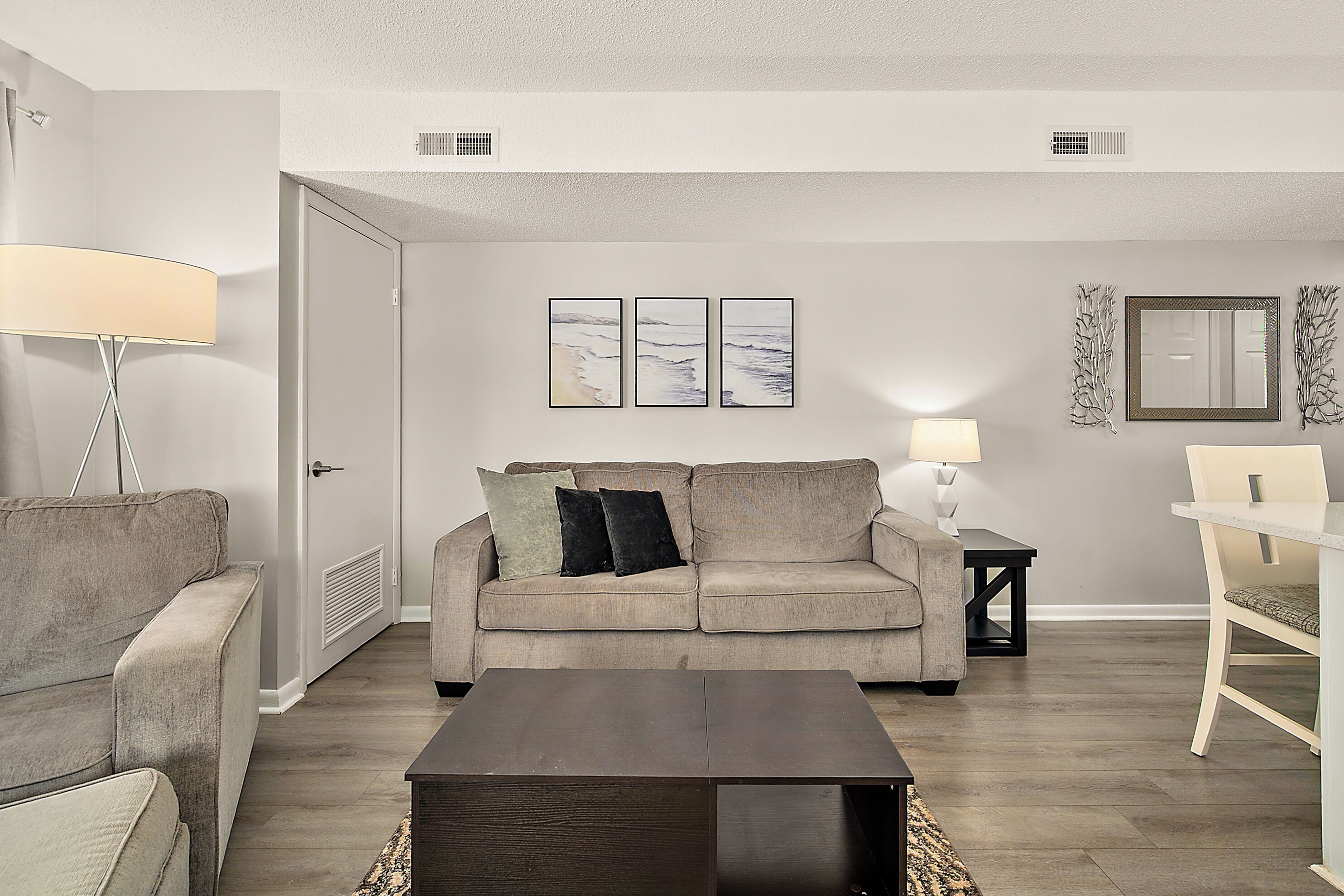 A living room with a sofa, a coffee table, a lamp, and wall art.