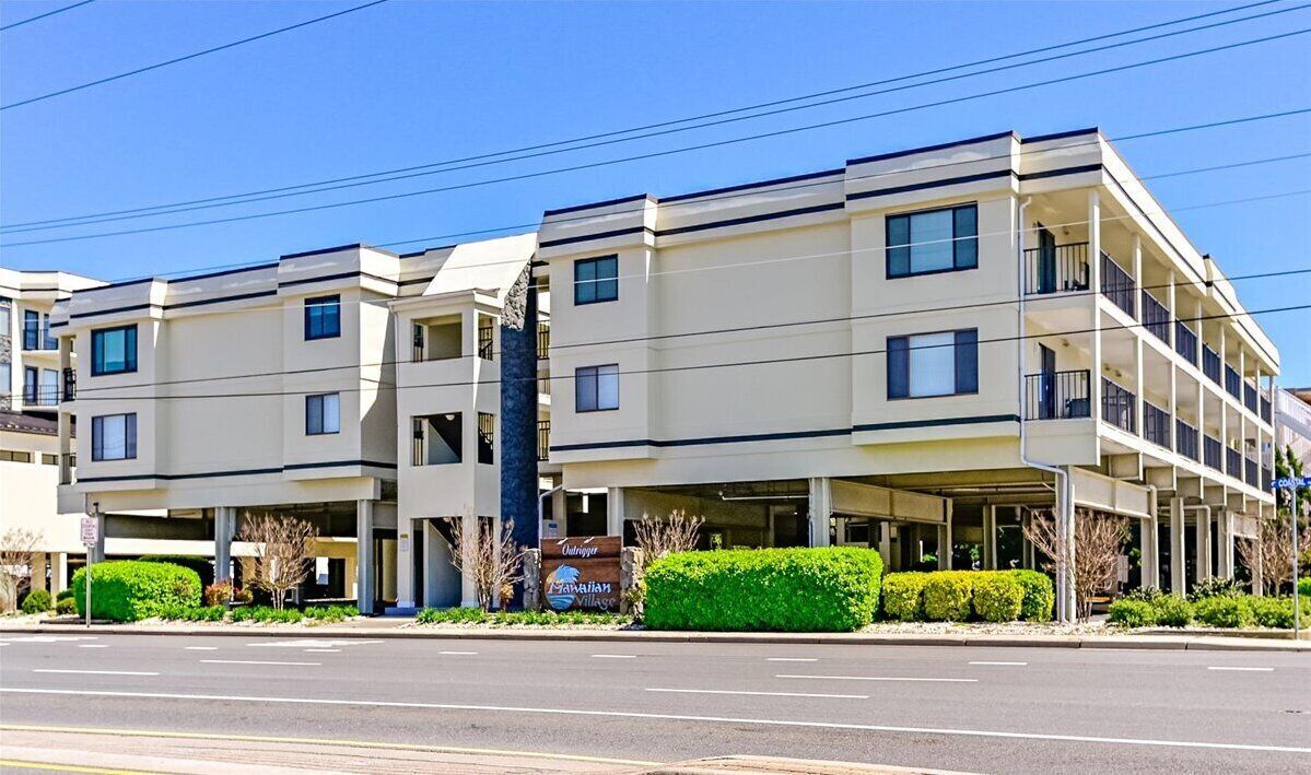 A multi-story hotel with a flat facade, multiple balconies, and a sign indicating it is a Hawaiian Village.