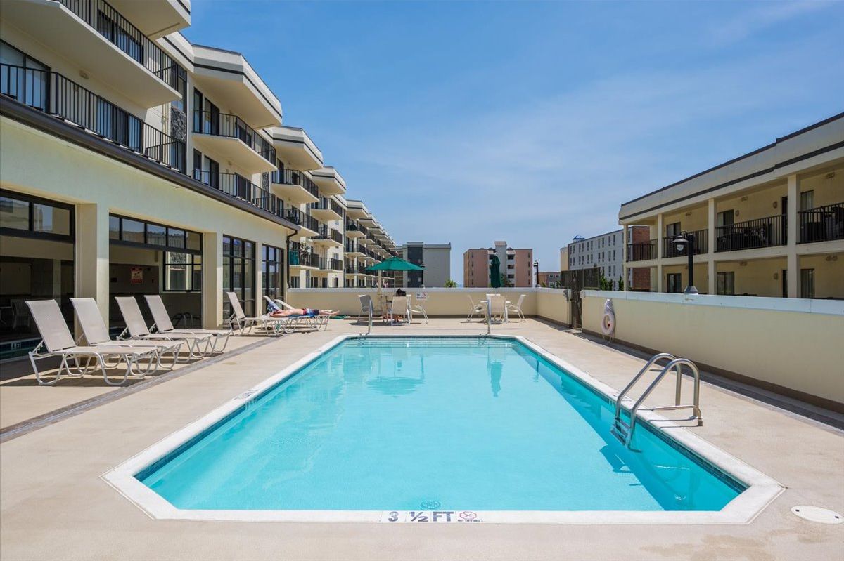 A swimming pool with lounge chairs and a clear blue sky.