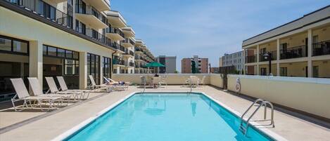 A swimming pool with lounge chairs and a clear blue sky.