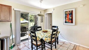 A dining area with a table set for four, a ceiling light, and a painting on the wall. - Refreshing Oasis with Massage Chair, Game Garage, Large Fenced Yard +Retro games (Longwood)