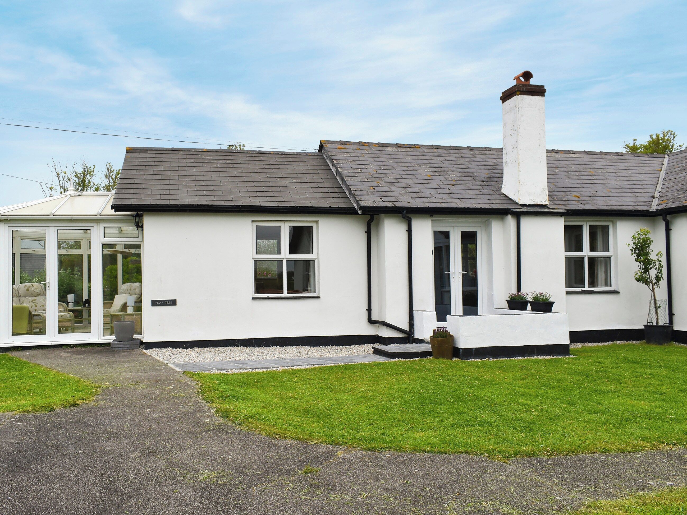 A single-story house with a conservatory, a front door, and a small garden area.
