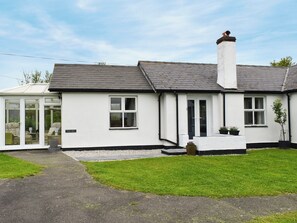 A single-story house with a conservatory, a front door, and a small garden area.
