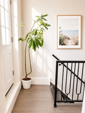 A staircase with a black railing, a potted plant, and a framed picture on the wall.
