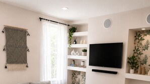 Una sala de estar moderna con un sofá, una mesa de centro, un televisor y una estantería.