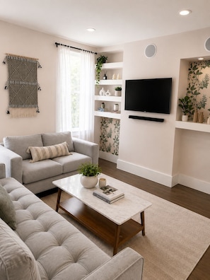 A modern living room with a sofa, a coffee table, a TV, and a bookshelf.