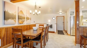 Un espace repas comprenant une table et des chaises en bois, un lustre et des œuvres d’art accrochées au mur.