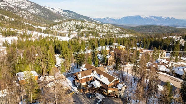 A residential area with multiple houses surrounded by snow-covered mountains and dense forests. - New Listing! Three Bedroom Apartment, Sleeps 6, Steps to Ski Access (Whitefish)