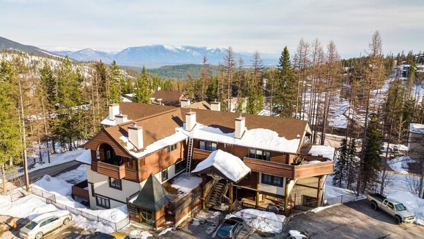 A multi-story lodge with a ski lift, surrounded by snow-covered trees and mountains in the background. - New Listing! Three Bedroom Apartment, Sleeps 6, Steps to Ski Access (Whitefish)