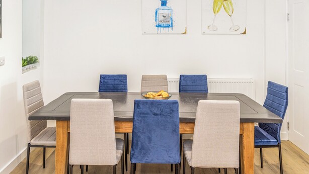 Ein Essbereich mit einem rechteckigen Tisch, sechs Stühlen und zwei an der Wand befestigten Kunstwerken.