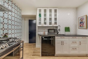 A modern kitchen with white cabinetry, a microwave, and a stainless steel dishwasher.