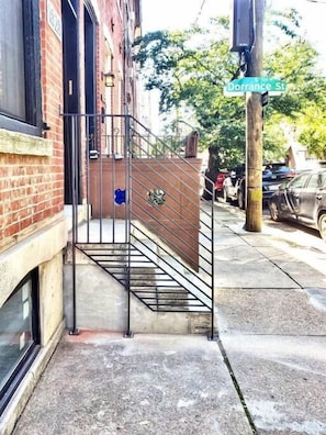 A staircase leading to a building entrance, a street sign for Dorrance St, and parked cars on the sidewalk.
