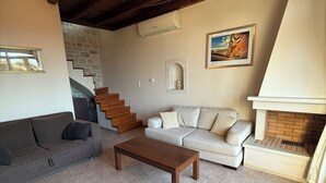 Una sala de estar con techo de madera, chimenea, una escalera y un sofá.