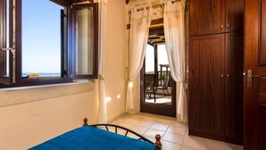 Un dormitorio con cama, ventana, puerta y vistas al exterior.