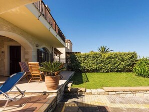 Un immeuble doté d’un balcon, d’un espace extérieur aménagé pour s’asseoir et d’une pelouse bien entretenue.