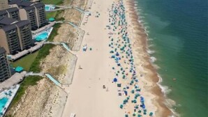 Une vue aérienne d’une plage où l’on voit de nombreux parasols et des gens.