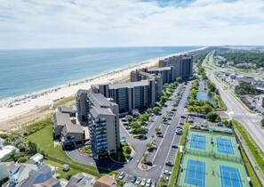 Una zona residenziale costiera con edifici alti, una spiaggia e un campo da tennis.