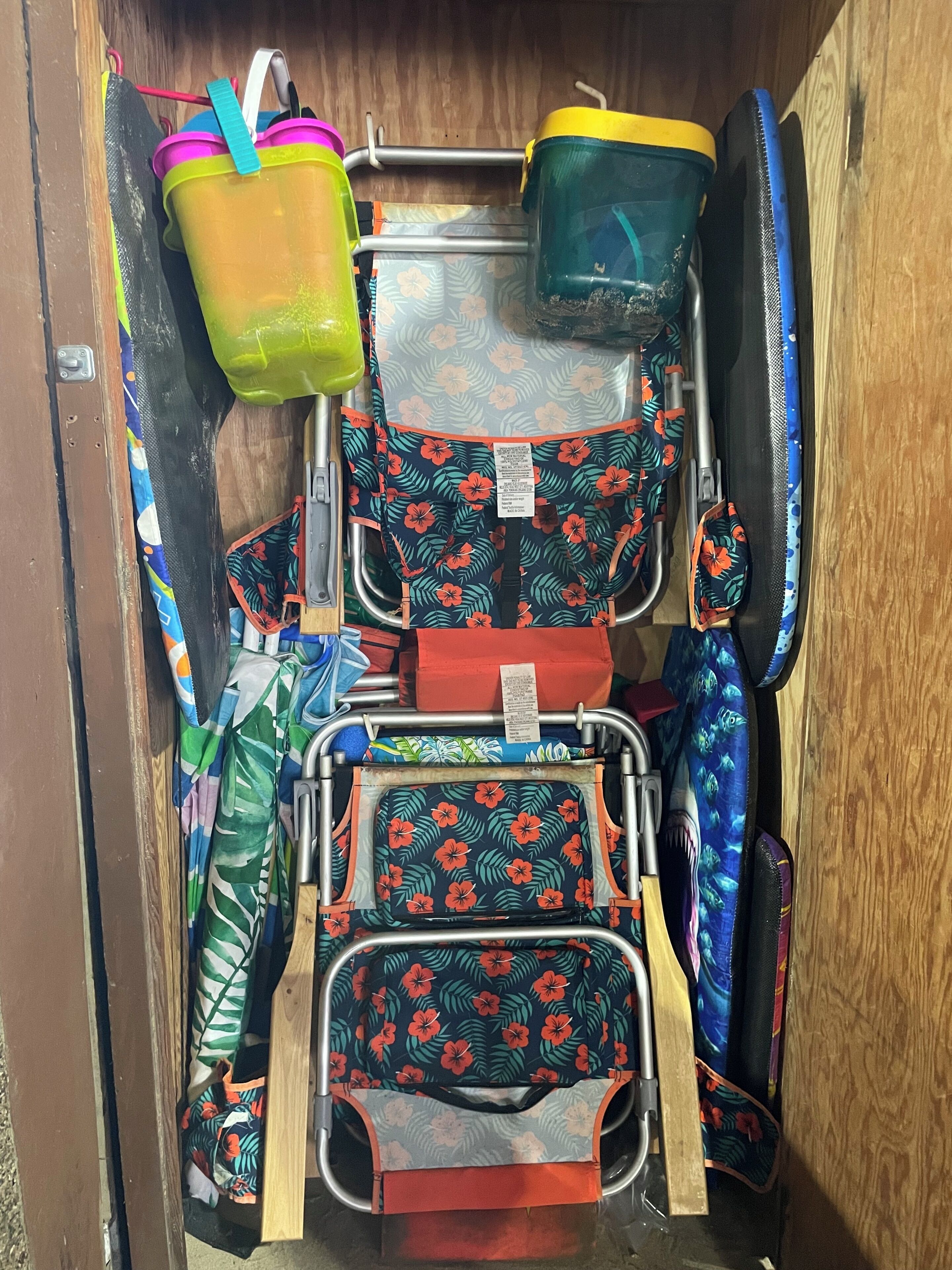 Un compartiment de rangement contenant divers objets, notamment un récipient en plastique vert, un récipient bleu et plusieurs sacs à motifs floraux.