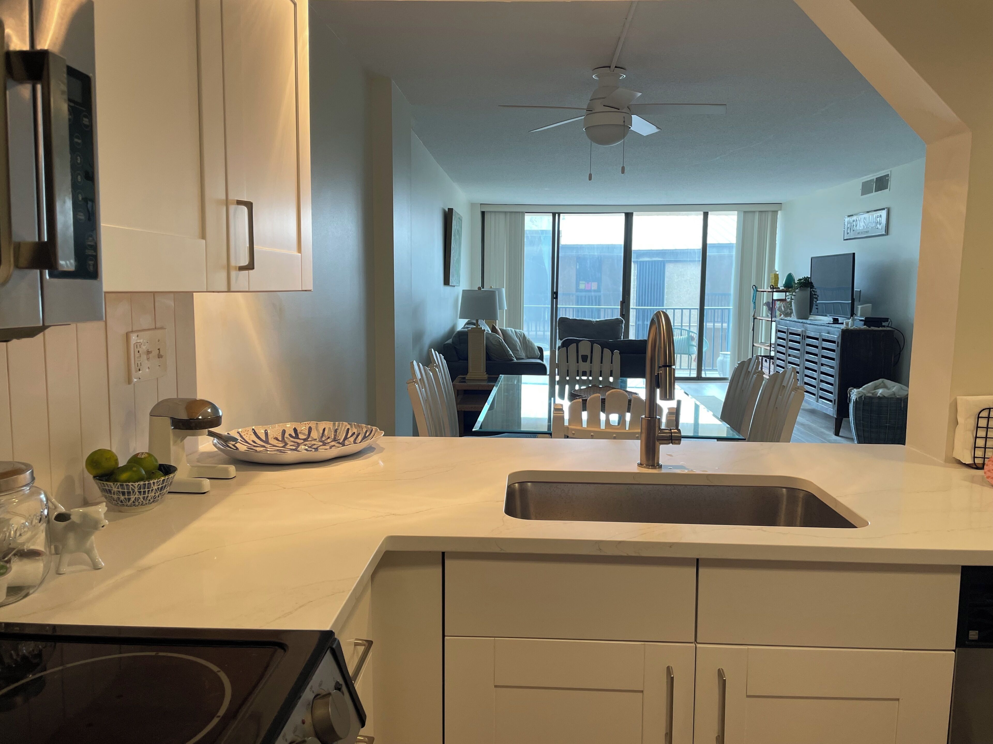 Une cuisine moderne dotée d’un îlot central, d’un coin repas avec une table en verre et d’une vue sur l’extérieur.