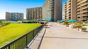 Un complexe hôtelier moderne comprenant plusieurs immeubles de grande hauteur, une cour centrale avec une pelouse et des espaces de détente en plein air dotés de parasols.