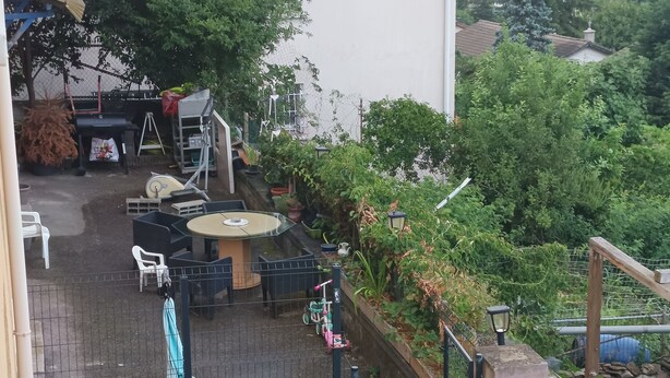 An outdoor patio area with a round table and chairs, surrounded by potted plants and a fence. - Studio Welcome to Keylia (Saint-Étienne)