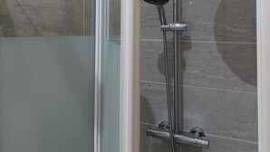 A glass-enclosed shower area with a handheld showerhead and a wall-mounted rain showerhead. - Studio Welcome to Keylia (Saint-Étienne)