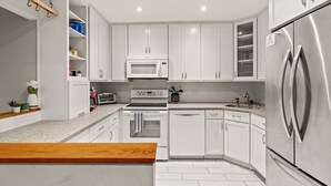 Een moderne keuken met witte kasten, roestvrijstalen apparatuur en een houten aanrecht.