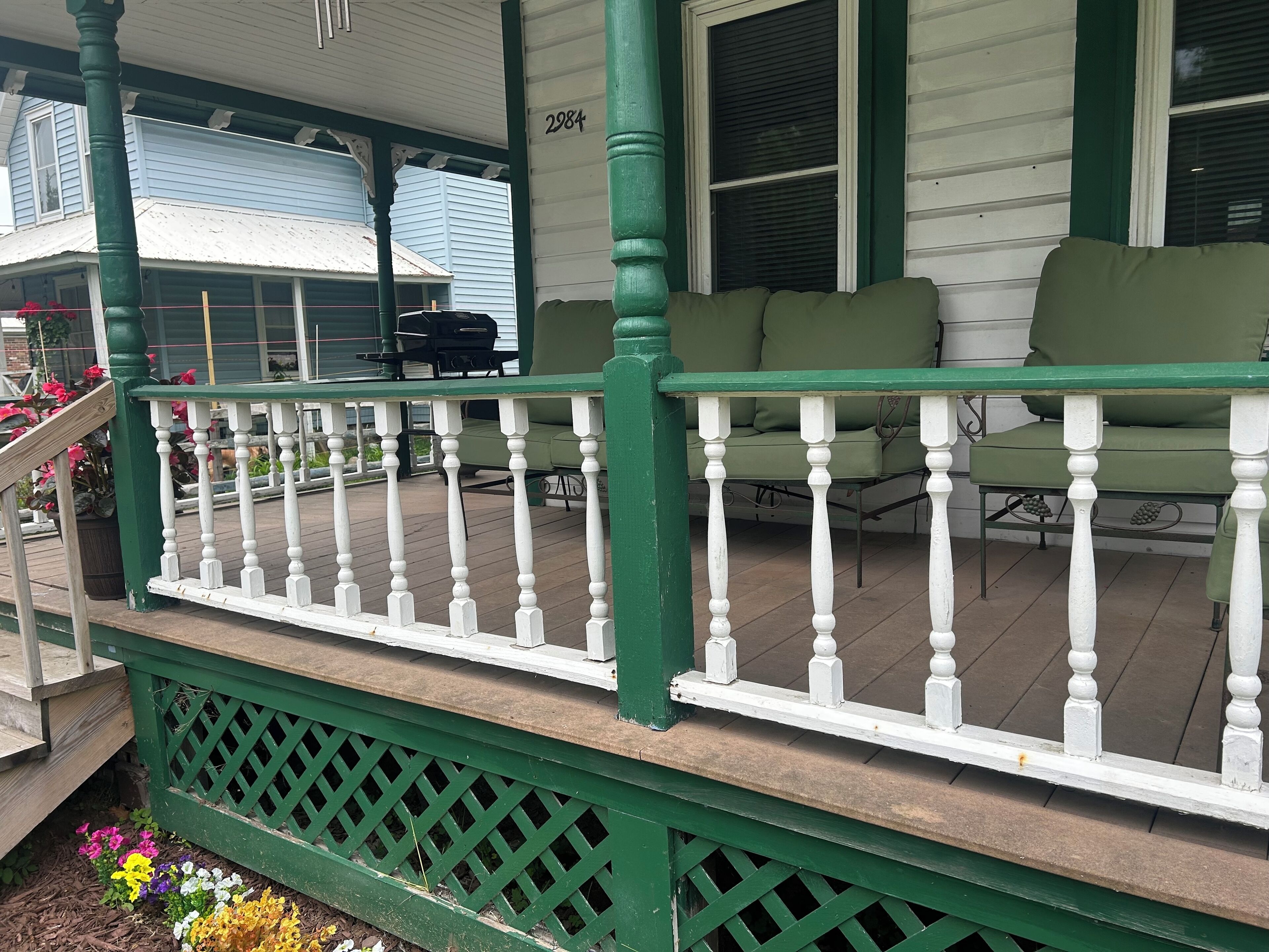 A porch with a green railing, a green bench, and a number '2984' on the wall.