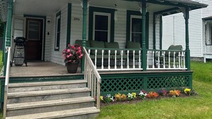 A two-story house with a porch, green trim, and a number '285' on the front. - The Guides House • Cozy Main St Stay with Porch Views (Old Forge)