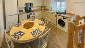 Une cuisine compacte comprenant une table à manger, des chaises, un lave-linge et une fenêtre.