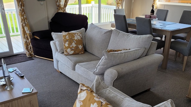 A living room with two grey sofas, a black armchair, a wooden coffee table, and a dining table with chairs. - Remarkable 3-bed House in Hull (Hull)