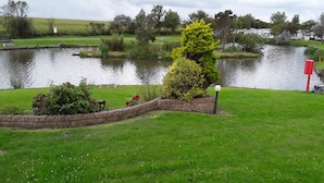 A serene lakeside setting with a stone wall, a lamp post, and a small bench. - Remarkable 3-bed House in Hull (Hull)
