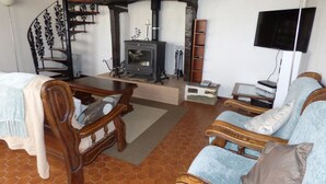 Una sala de estar con chimenea, muebles de madera y televisor.