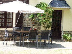 Een terras met een stenen muur, een houten tafel en metalen stoelen.
