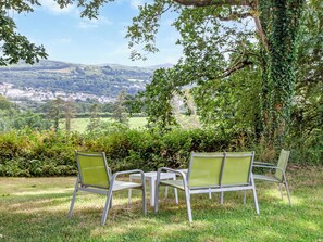 A table and four chairs set outdoors with a view of a valley and distant buildings. - East Hook Holiday Cottages - Clover Cottage (Okehampton)