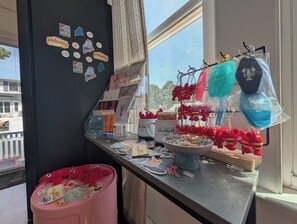 Een etalage met verschillende spullen, waaronder een roze bak met stickers, een mok en sleutelhangers.