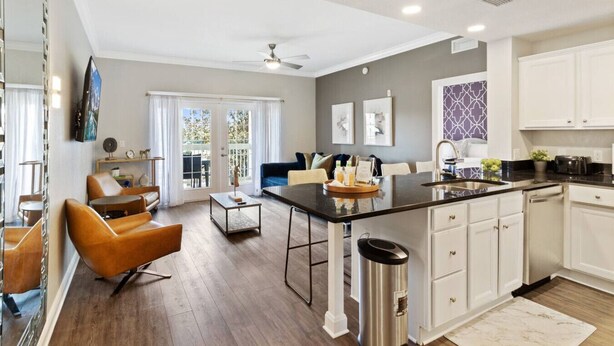 A modern kitchen with a central island, white cabinetry, and a dining area with leather chairs. - Modern 3-bed, 2-bath condo minutes from Disney! (Kissimmee)