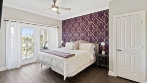 A bedroom with a bed, a ceiling fan, a nightstand, and a door. - Modern 3-bed, 2-bath condo minutes from Disney! (Kissimmee)