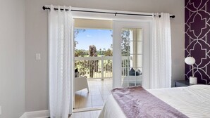 A bedroom with a bed, a balcony with a view of trees and a clear sky. - Modern 3-bed, 2-bath condo minutes from Disney! (Kissimmee)
