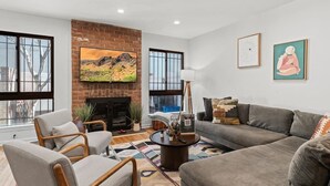 A living room with a fireplace, a sofa, a coffee table, and a large window.