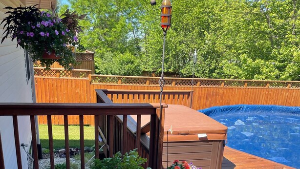 Una terraza de madera con plantas en macetas, un jacuzzi y una piscina.